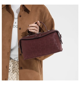 Detail of burgundy leather handbag with subtle leopard texture and metallic double zippers