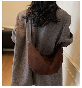 Close-up of deep brown suede crescent bag worn with a grey tweed blazer for vintage style