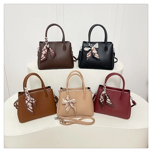 Five minimalist textured leather bucket bags in various colors with decorative silk scarves