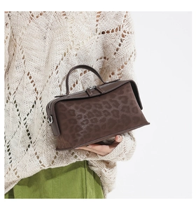 Detail of leopard print shoulder bag with double zipper and metal hardware held by a model