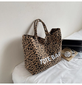 Close-up of leopard print canvas tote bag with white TOTE BAG text and laptop