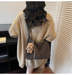 Vue détaillée du grand sac croissant marron foncé avec charme ours et bandoulière