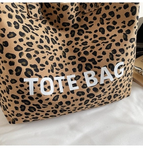 Detailed macro of leopard print canvas tote bag featuring bold white TOTE BAG lettering