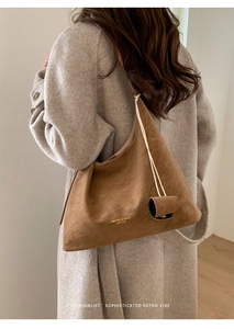 Brown vintage leather tote bag shown on model in a minimalist indoor setting