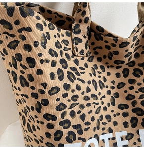Detail of leopard print canvas tote bag featuring premium stitching and white typography