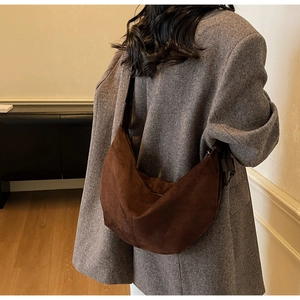 Detail of deep brown suede hobo bag shown on shoulder over a stylish grey wool coat