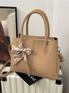 Minimalist beige pebble leather bucket bag with silk scarf on handle and shoulder strap