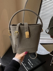 Gray textured leather bucket handbag with gold hardware and adjustable crossbody strap