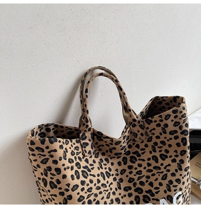 Detail of leopard print canvas tote bag featuring robust handles and white text branding