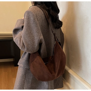 Detail view of large dark brown suede hobo bag with sleek shoulder strap on a model