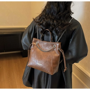 Dettaglio della borsa tote vintage in pelle marrone con catene d'argento e coulisse laterali