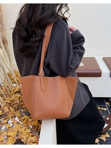 Outdoor shot of a brown leather tote bag with white stitching and silver metal buckle