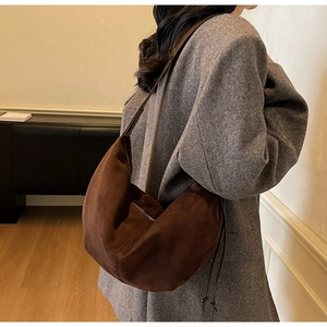 Detailed side view of the dark brown suede hobo bag with drawstring and zip details