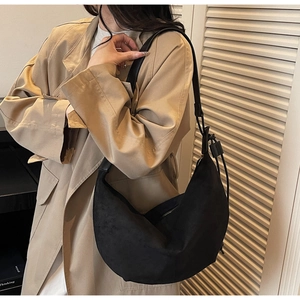 Close-up of black suede hobo bag with a wide shoulder strap and matte texture