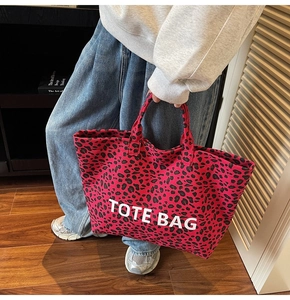 Detail showing the large red leopard print canvas tote bag with 'TOTE BAG' white text
