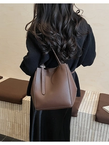 Detail of a large brown tote bag with contrast stitching on high-quality pebbled leather