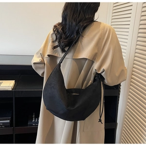 Detail of a black hobo bag showing its soft suede-like texture and side drawstring accents