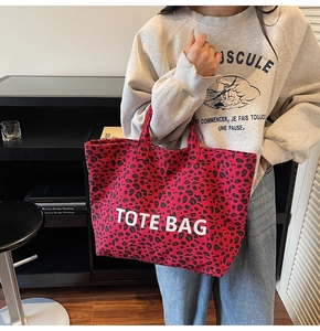 Detailed close-up of a large red leopard print canvas tote bag with bold white text