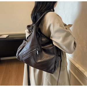 Detail of a dark brown pebble faux leather tote bag with functional front zipper pocket