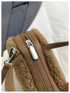 Detail of brown faux sherpa plush bag with silver zipper and premium leather piping