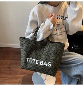 Detail view of leopard print canvas tote bag with white TOTE BAG text carried by model