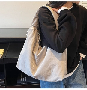 Detailed side view of grey oversized canvas tote bag with textured finish on model