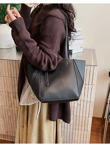 Close-up of black leather tote bag with contrasting white stitching and long shoulder strap