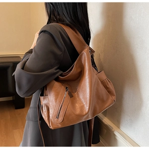 Detailed side view of caramel leather hobo bag with zip pocket on female model
