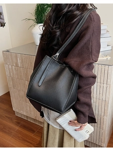 Detail of black pebbled leather tote with contrast stitching and silver metal accents