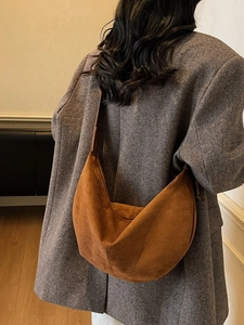 Brown suede crescent bag worn by model with autumn coat, showing large capacity and texture