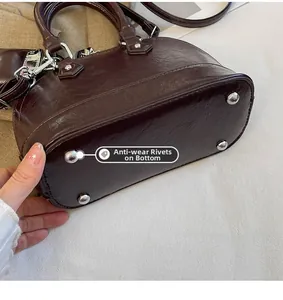Vue détaillée des quatre clous en métal argenté sur le fond du sac à main en cuir marron