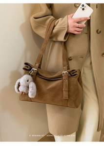 Brown suede tote bag detail with adjustable buckle and cute plush rabbit charm accessory