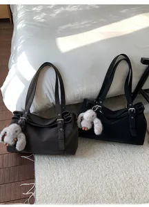 Détail de cabas rétro noir et marron avec pendentifs lapin en peluche sur un tapis