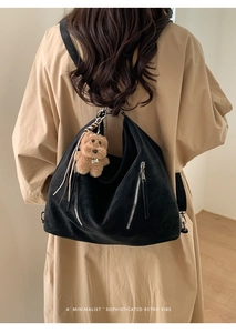 Close-up of black retro tote bag with dual silver zippers and a cute teddy bear charm