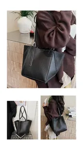 Detailed view of black tote bag featuring white contrast stitching and lychee leather texture