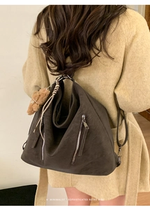 Detail of dark brown vintage tote bag with zipper decor and plush charm on matte leather