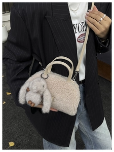 Detail of plush crossbody bag with bunny pendant and faux fur texture on a model