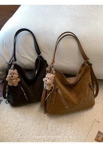 Detail of vintage tote bags with matte PU texture and plush bear charms on a white bed