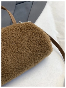 Detail of soft brown faux shearling texture with leather strap and silver D-ring