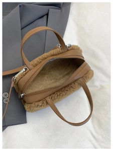 Detail view of brown plush handbag with leather handles and metallic zipper closure