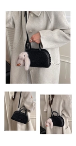 Detail of black plush handbag with pink bunny charm and adjustable leather strap