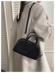 Detail of black faux fur plush handbag showing soft texture and leather fashion label