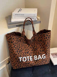 Brown leopard print canvas tote bag with white TOTE BAG text on a cozy dark background