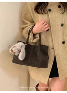Detail of retro dark brown suede tote bag with white faux fur charm on beige wool coat