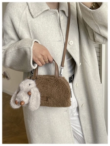 Close-up of brown plush crossbody bag with leather handles and cute rabbit charm