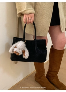 Detail of black suede tote bag with metal ring and fluffy bunny plush pendant
