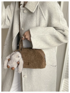 Detail of brown faux fur crossbody bag featuring a cute white bunny charm and leather label