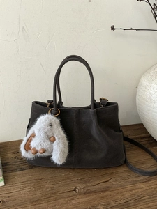 Vintage dark grey faux leather bucket bag with fluffy bunny charm on rustic wood