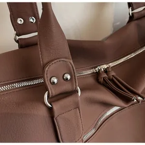 Close-up of brown leather bag showing silver hardware and stylish tassel zipper detail