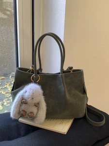 Dark green matte leather tote bag with plush rabbit charm and shoulder strap